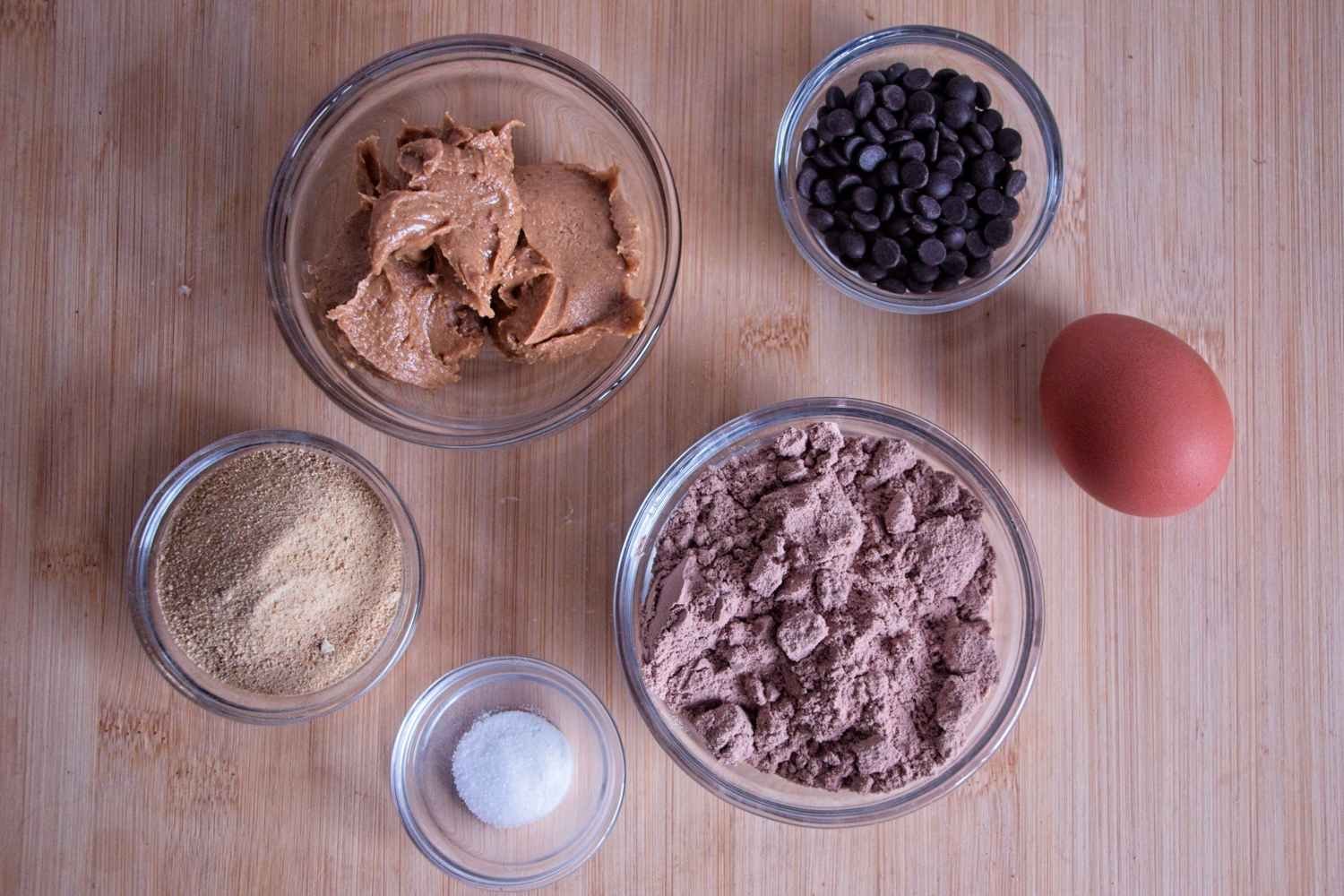 Ingredients for chocolate peanut butter protein cookies laid out on a wooden board