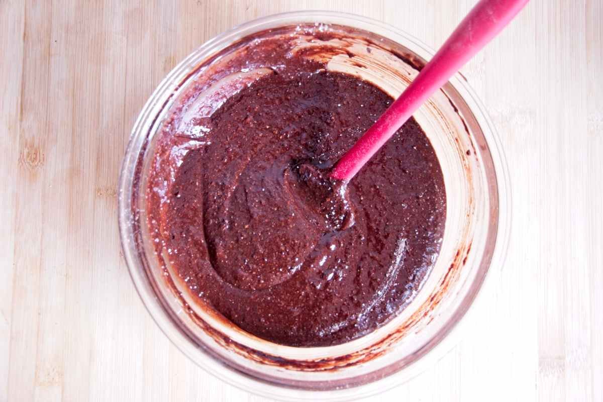 Thick chocolate brownie batter fully mixed and ready to bake in a glass bowl.