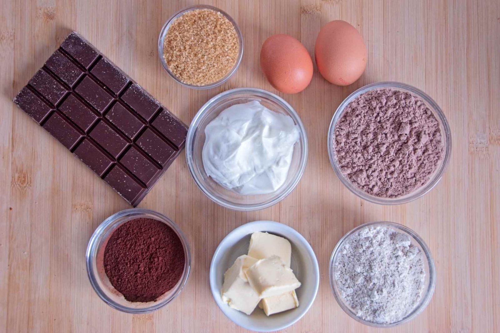 Measured ingredients for protein brownies laid out on a wooden board.