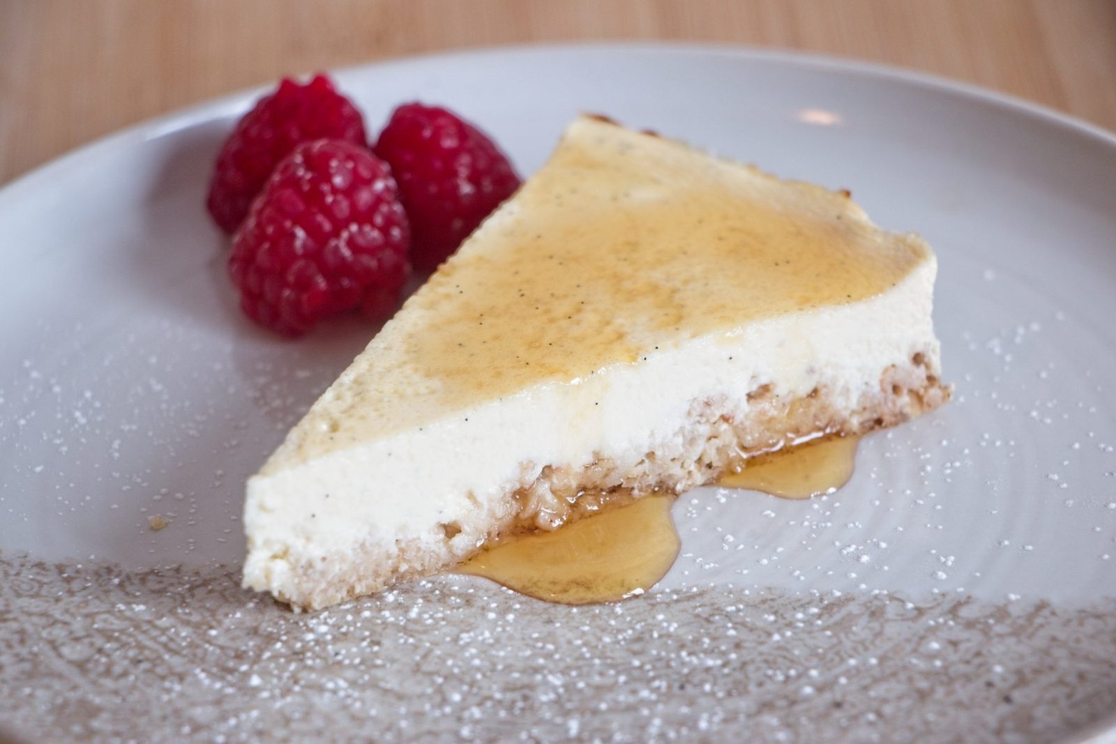 Protein cheesecake without protein powder showing a close-up of the creamy filling, oat base, honey drizzle, and fresh raspberries