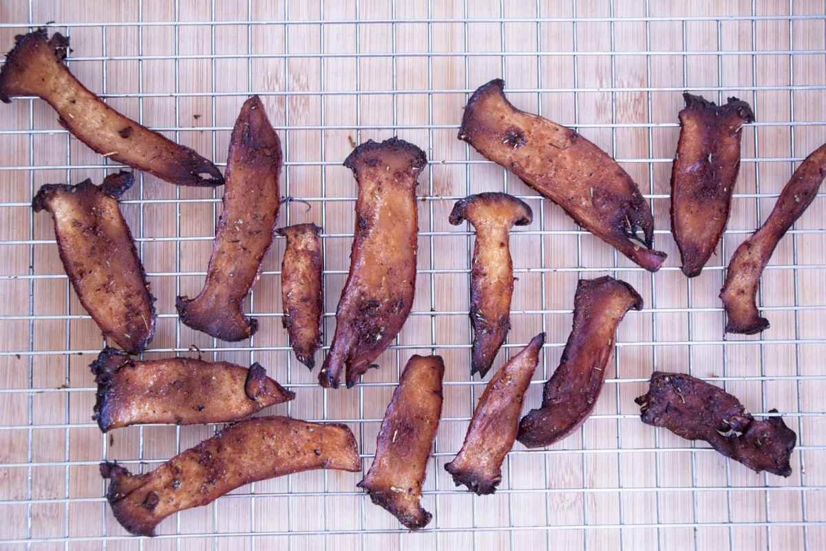 Overhead view of Crispy King Oyster Mushroom Bacon cooling on a wire rack after baking.
