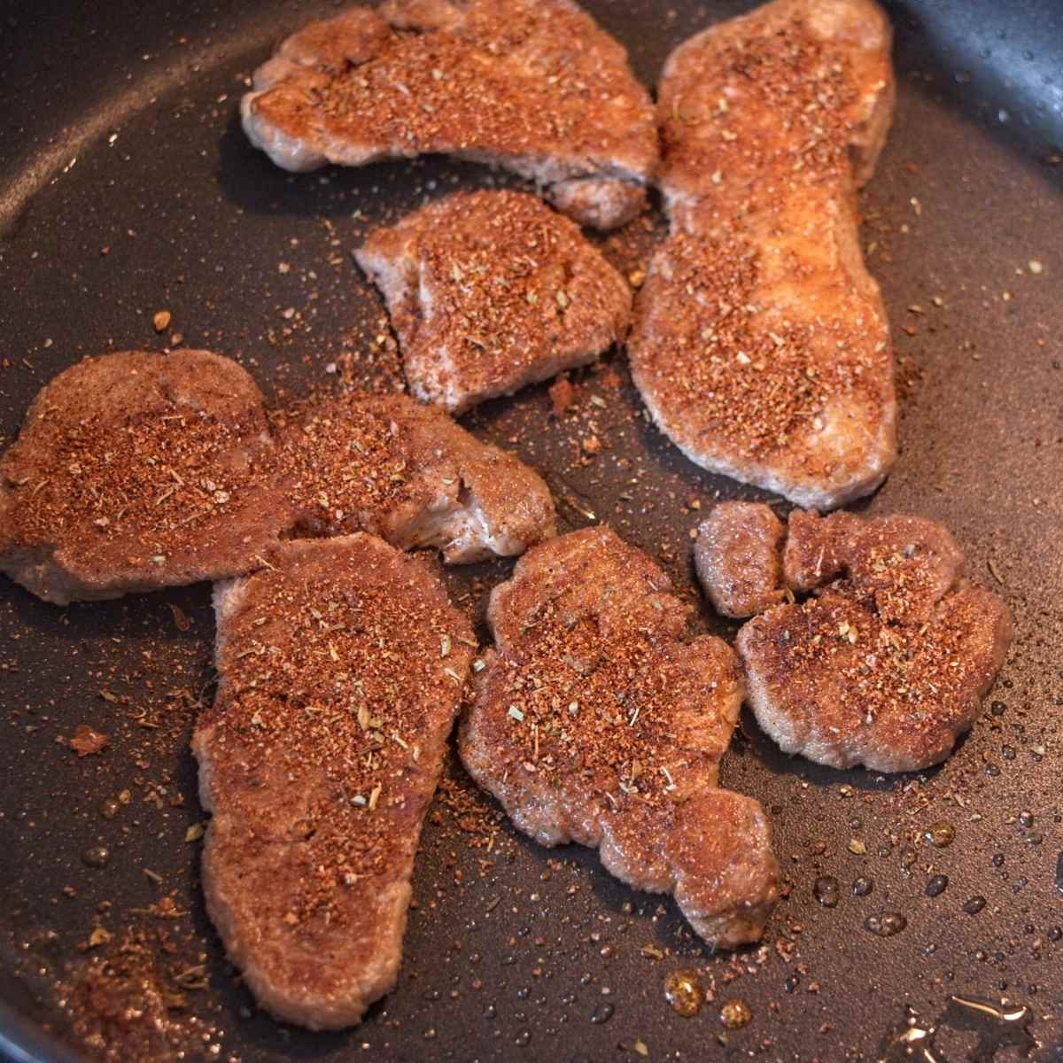 Crispy mushroom pieces seasoning in a pan during the final stage of cooking