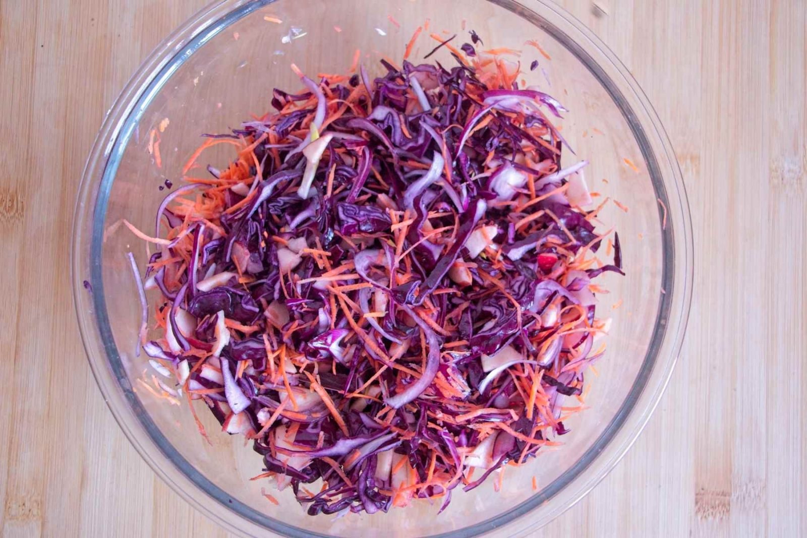 Grated carrot and sliced red cabbage mixed together in a glass bowl.