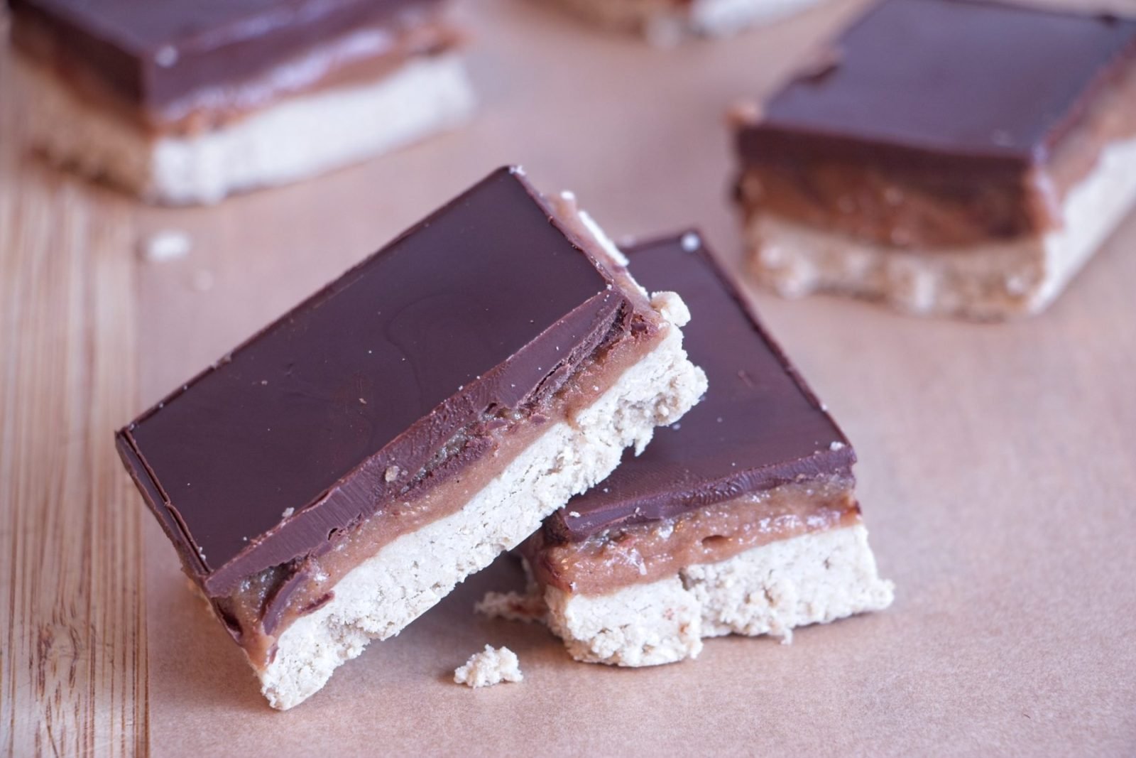 High protein millionaire’s shortbread stacked to show chocolate topping, caramel layer, and oat base
