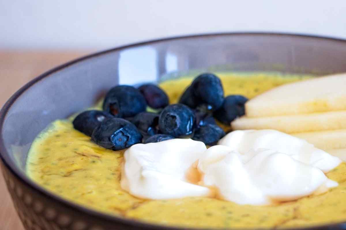 High protein oatmeal topped with blueberries, sliced apple and Greek yoghurt in a ceramic bowl.