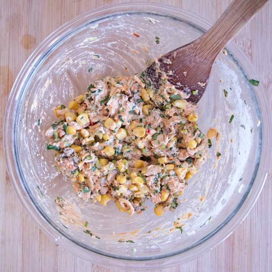 Thick fritter batter mixed with chopped lion’s mane mushroom, sweetcorn, and herbs in a glass bowl.