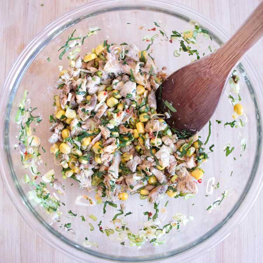Mixing chopped lion’s mane mushroom, sweetcorn, and herbs in a bowl before adding the flour batter.