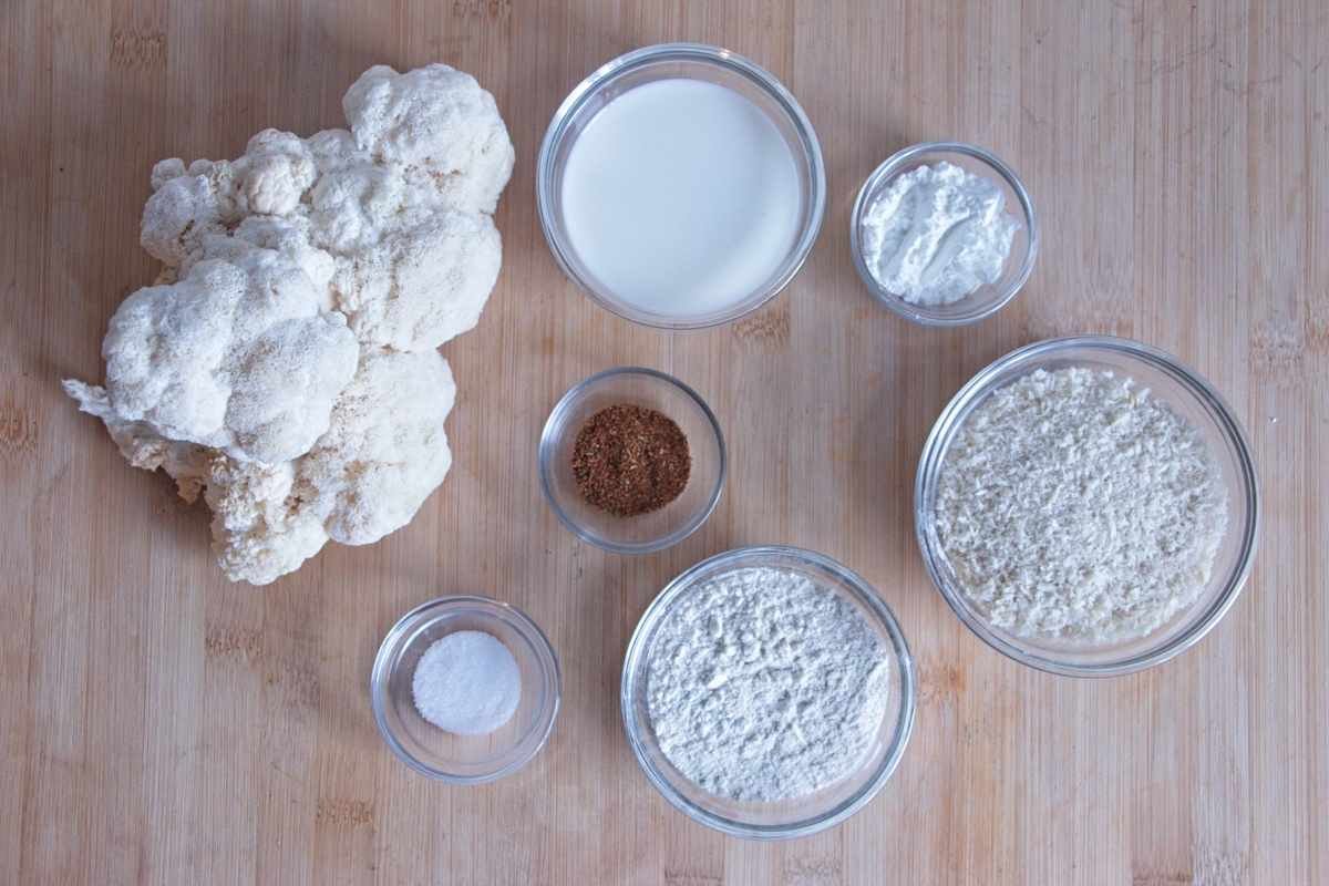 Ingredients for lion’s mane mushroom nuggets laid out on a board, including fresh mushroom, flour, cornflour, milk, seasoning, and panko breadcrumbs.