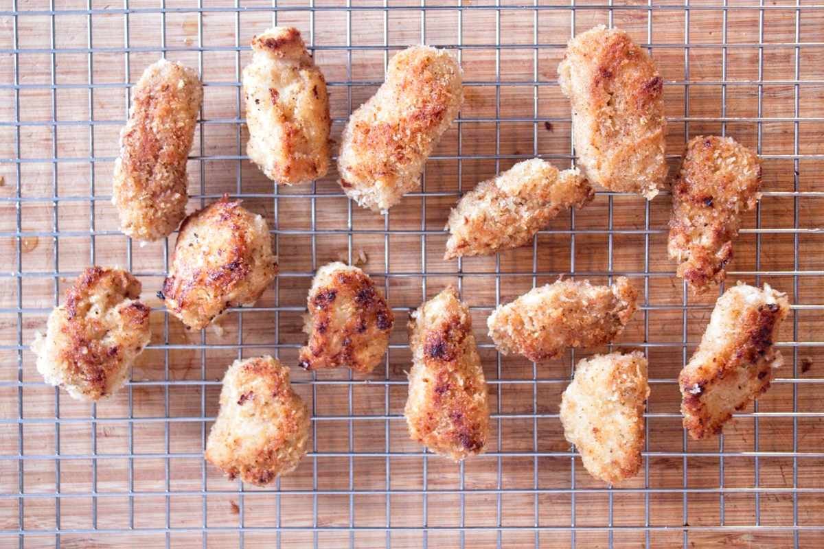 Lion’s mane mushroom nuggets resting on a wire rack after frying, deep golden and crisp on the outside.