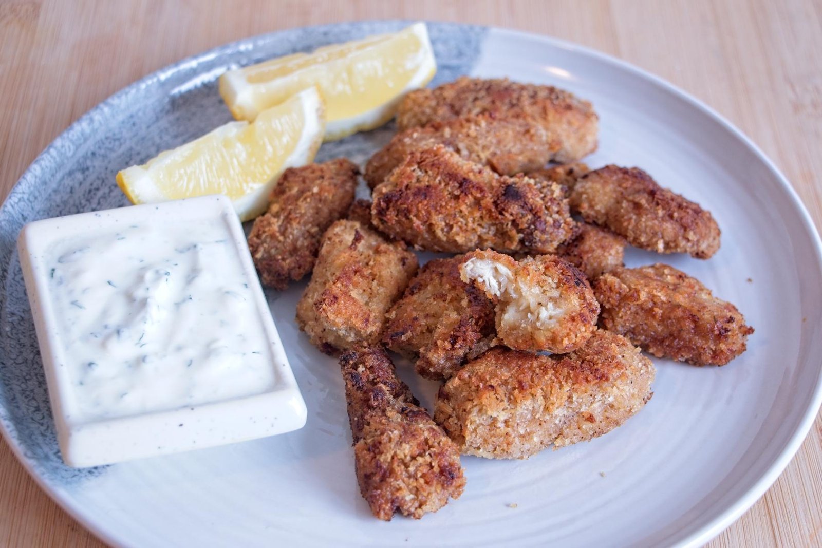 Lion’s mane mushroom nuggets served on a plate with creamy herb dip and lemon wedges, golden and crisp on the outside.