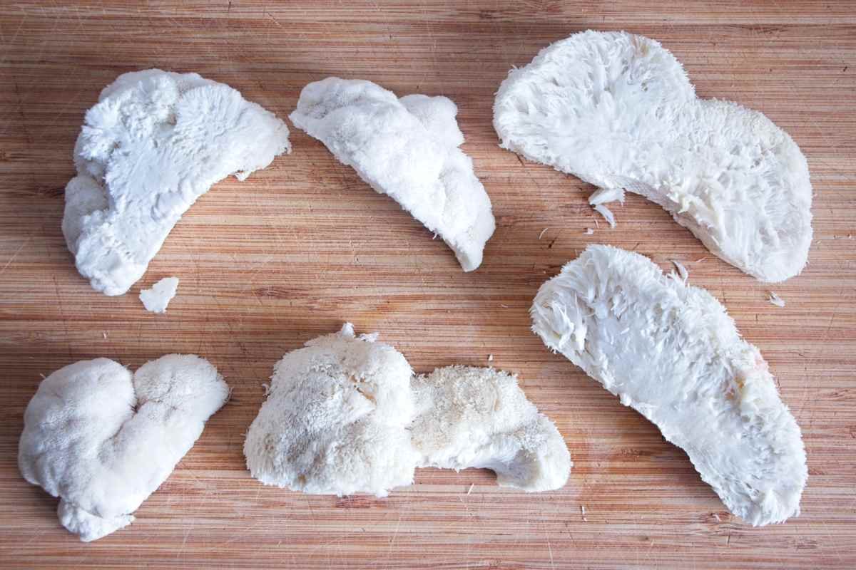 Prepared mushroom pieces laid out on a board after tearing into cooking-size portions