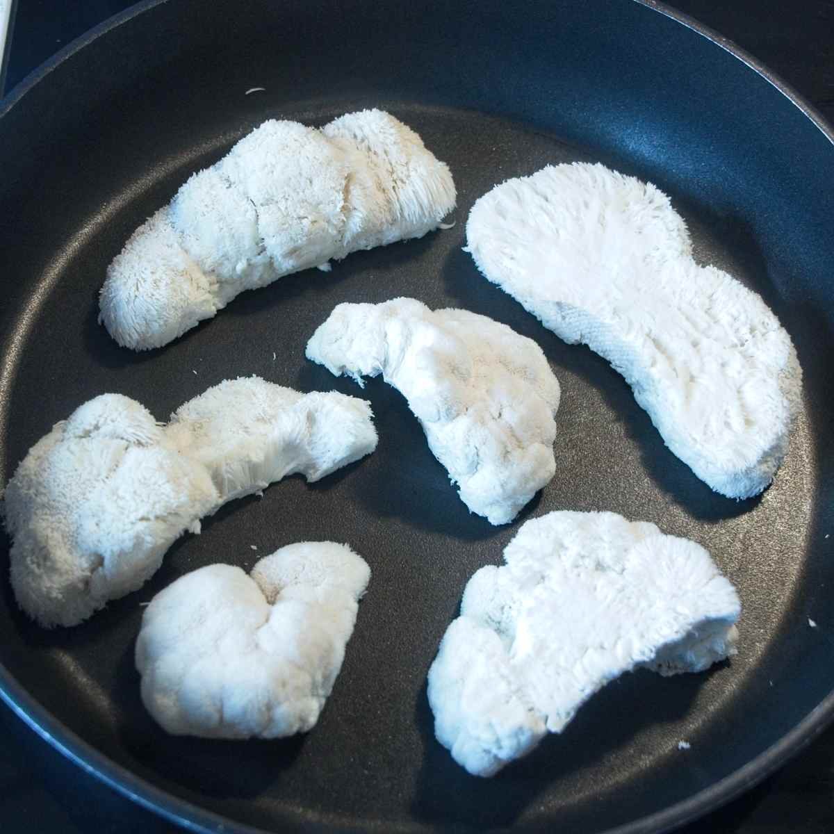 Raw mushrooms placed in a pan at the start of cooking before any browning