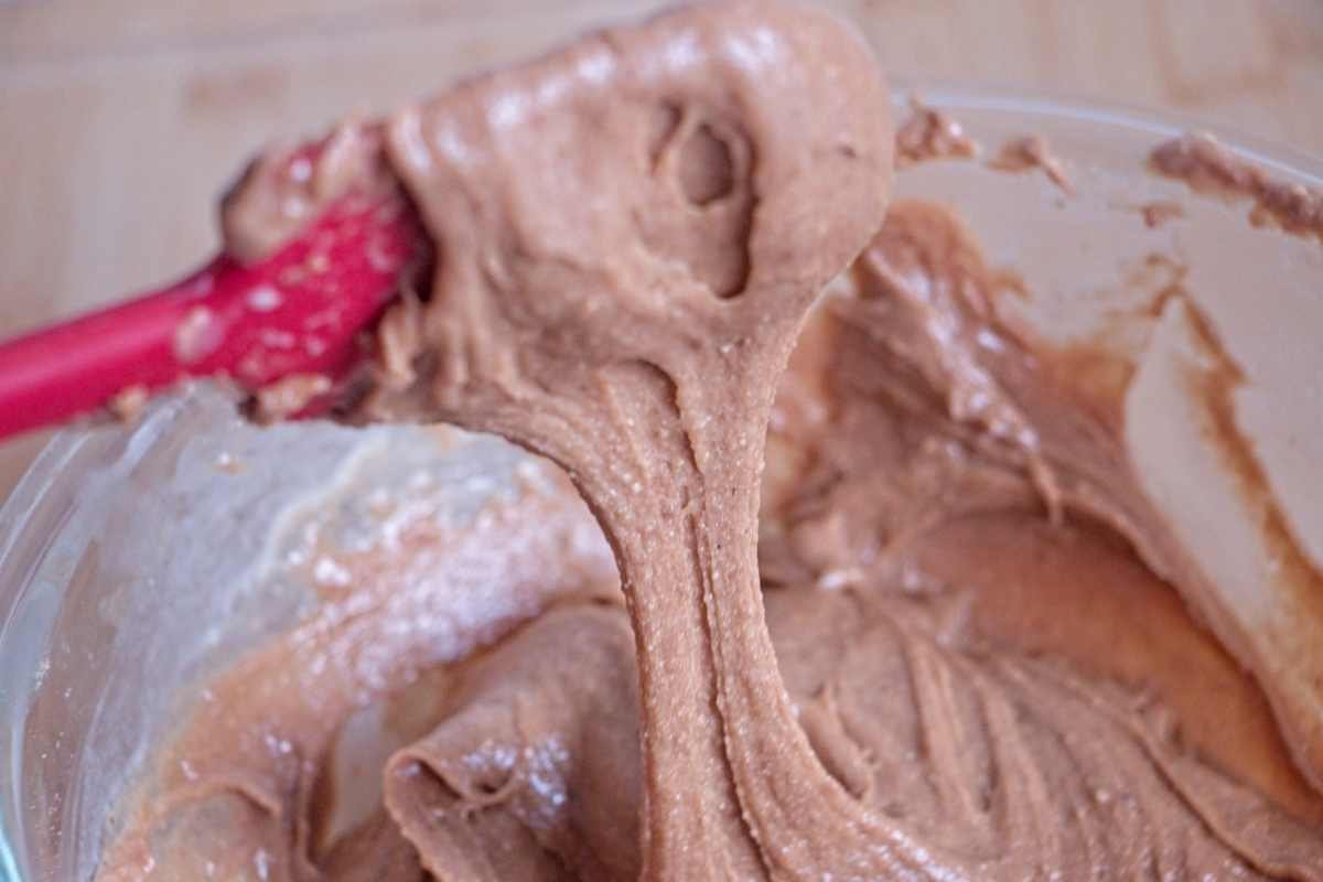 Thick cashew caramel mixture being stirred in a bowl, showing smooth, stretchy texture