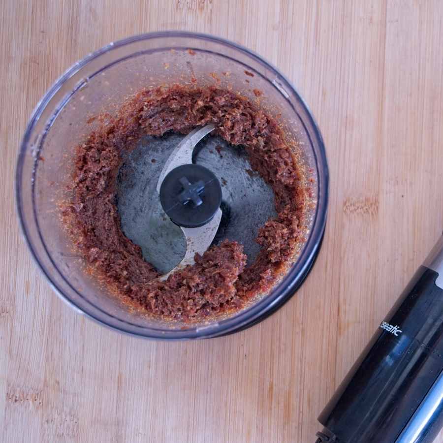 Medjool dates blended into a thick paste for the caramel layer in a small food processor bowl.