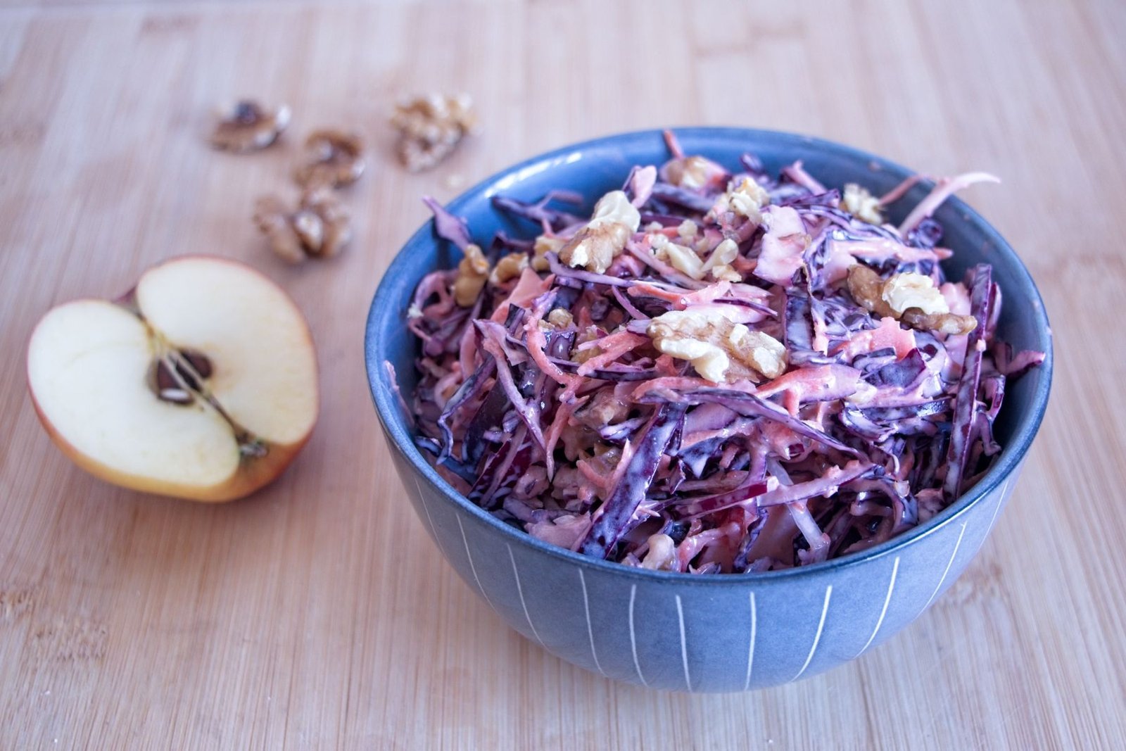 Winter coleslaw with red cabbage, apple, and toasted walnuts in a blue bowl, dressed with Greek yogurt.