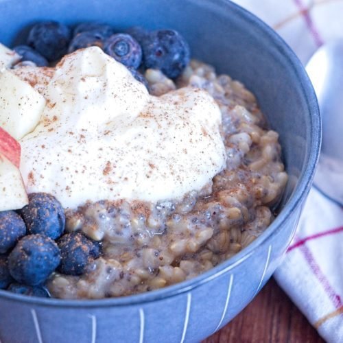 instant pot oat groats topped with yogurt, blueberries, diced apple, and cinnamon in a breakfast bowl