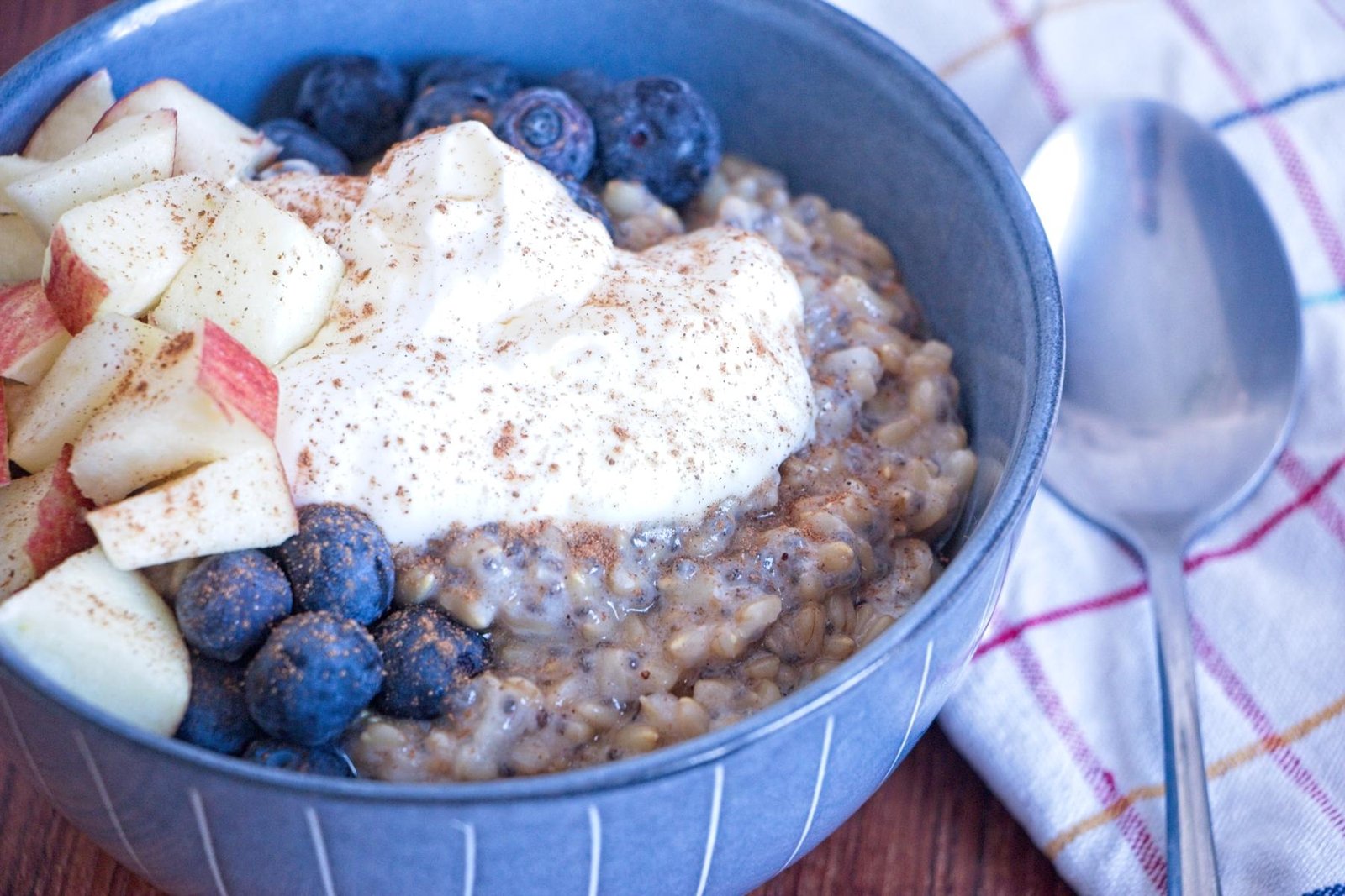 instant pot oat groats topped with yogurt, blueberries, diced apple, and cinnamon in a breakfast bowl