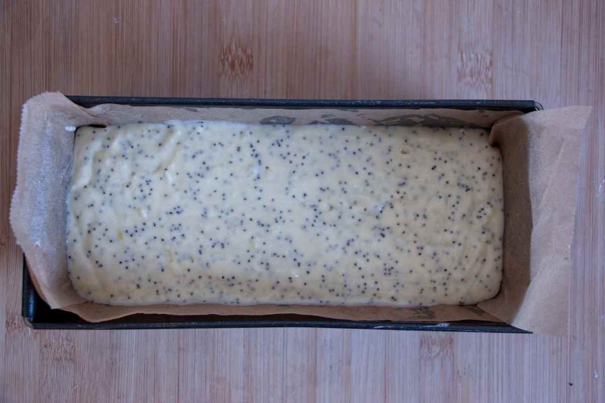poppy seed cake batter poured into a lined loaf tin ready for baking