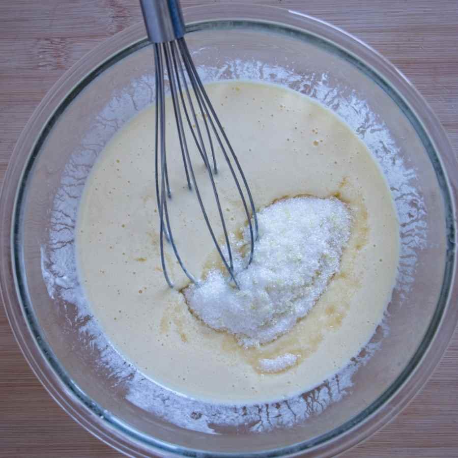 eggs, sugar, and yogurt mixture being whisked in a bowl for cake batter