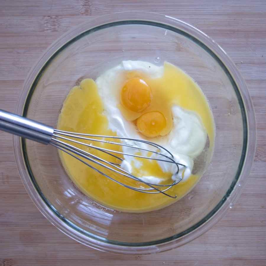 eggs, melted butter, and yogurt in a mixing bowl before whisking cake batter