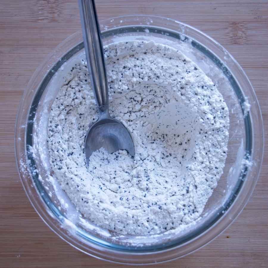 bowl of flour, baking powder, and poppy seeds mixed together for cake batter