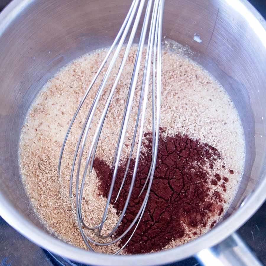 mixing lion’s mane mushroom powder and cacao in milk with whisk in saucepan