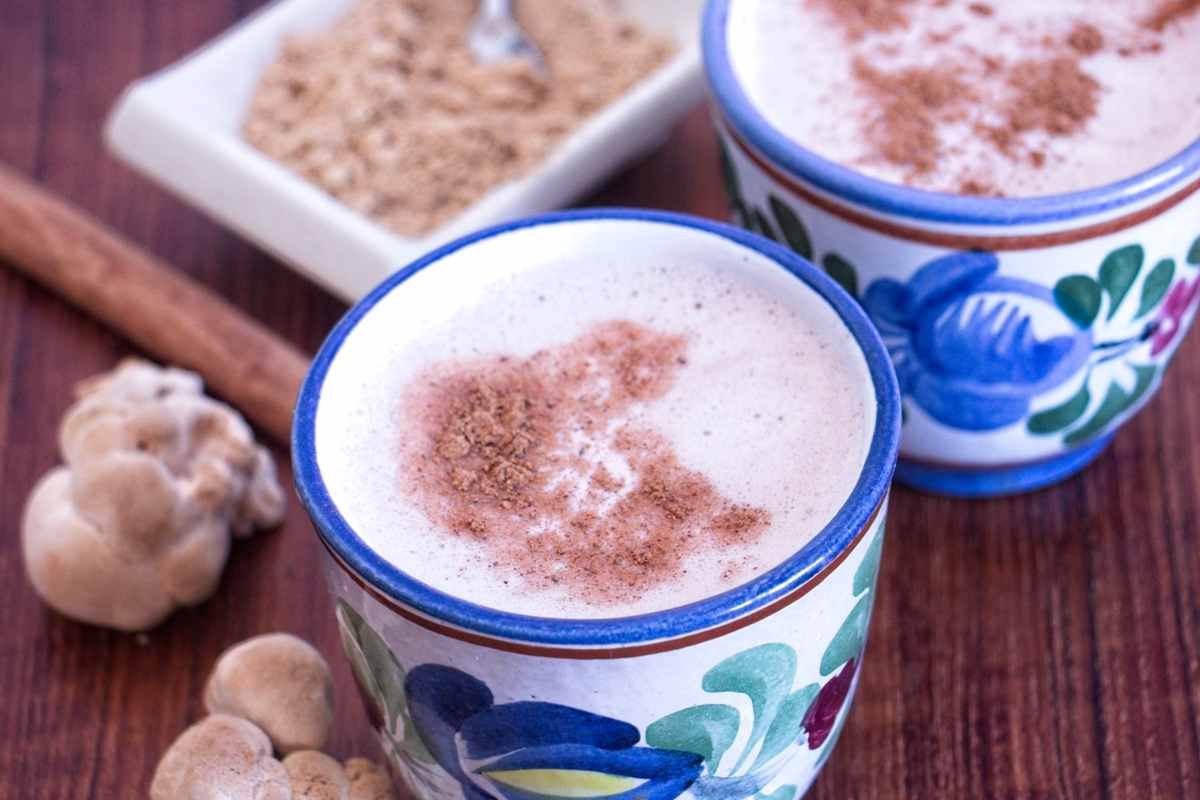 lion’s mane latte recipe served in ceramic cups topped with cinnamon, with fresh lion’s mane mushrooms and mushroom powder nearby