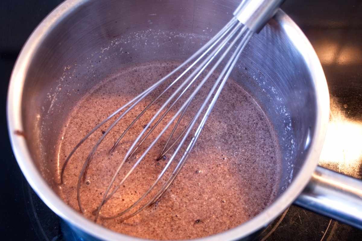 warming milk with cacao, cinnamon, and lion’s mane powder in saucepan while whisking