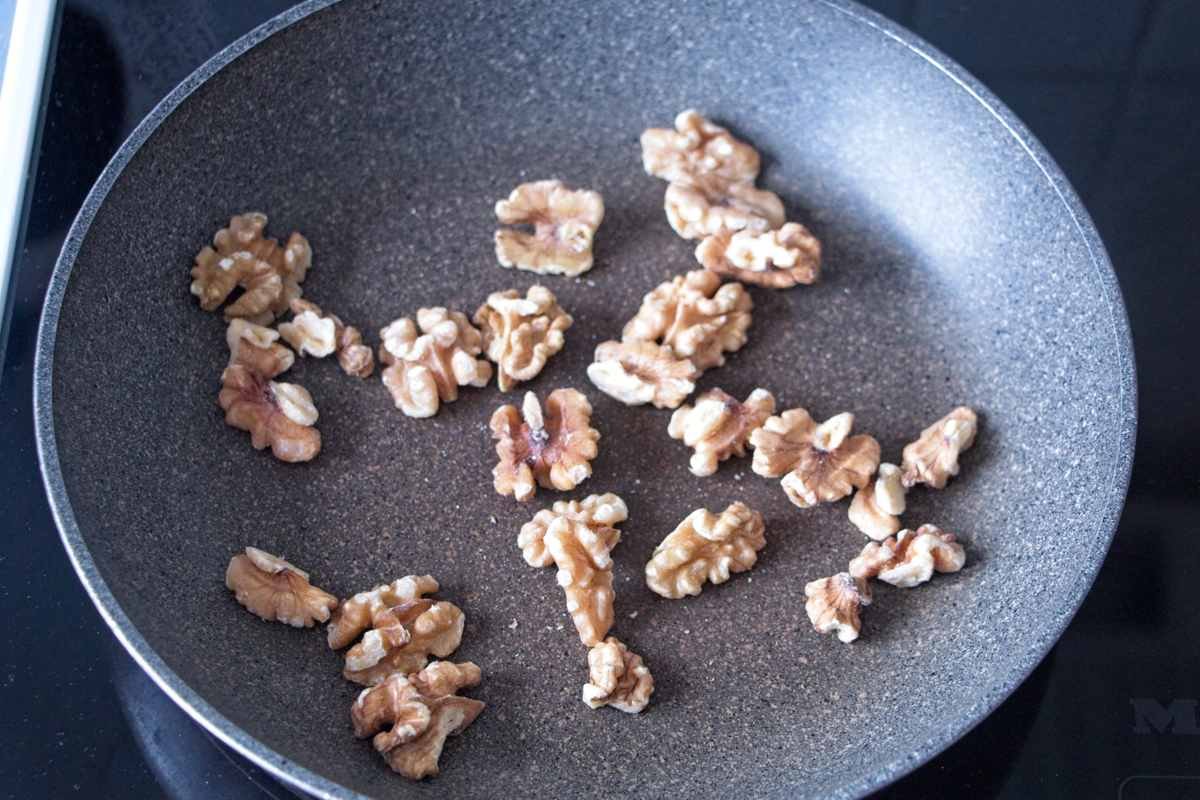 Walnuts toasting in a dry frying pan until lightly browned and fragrant