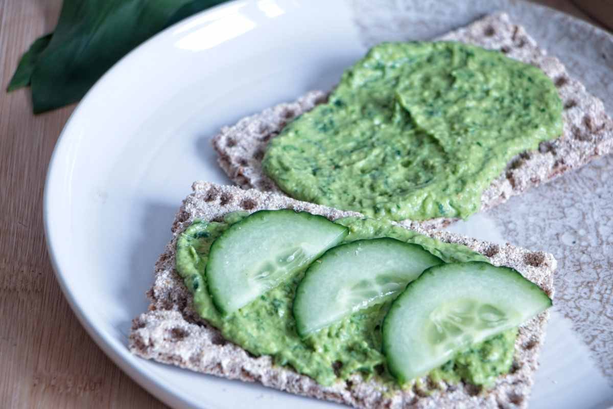 wild garlic hummus spread on rye crackers with sliced cucumber on top