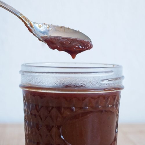 Homemade brown sauce recipe dripping from a spoon into a jar, showing thick, glossy texture