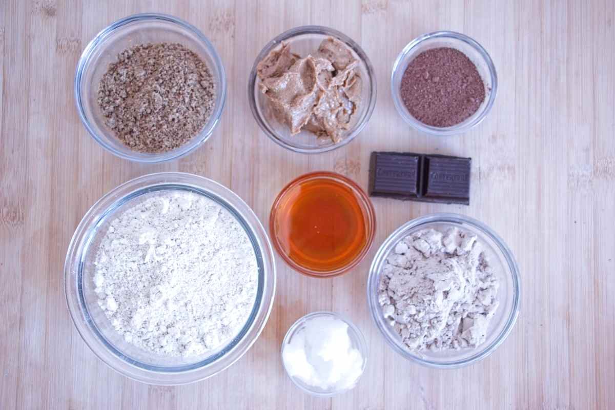 Ingredients for protein bars laid out including oat flour, peanut butter, maple syrup, protein powder and chocolate