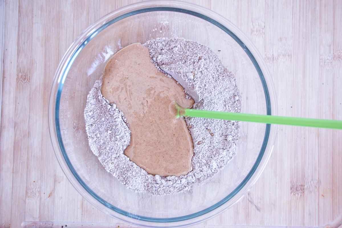 Wet ingredients being added to dry ingredients in a mixing bowl before combining
