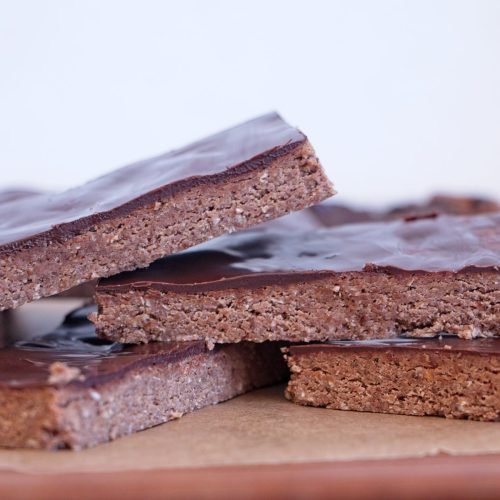 Chocolate peanut butter protein bars stacked with chocolate topping and a firm, sliceable texture