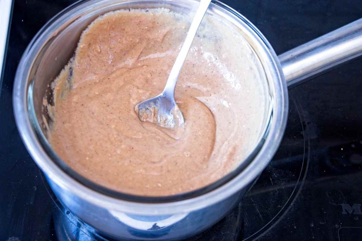 Peanut butter and syrup mixture being stirred in a saucepan until smooth