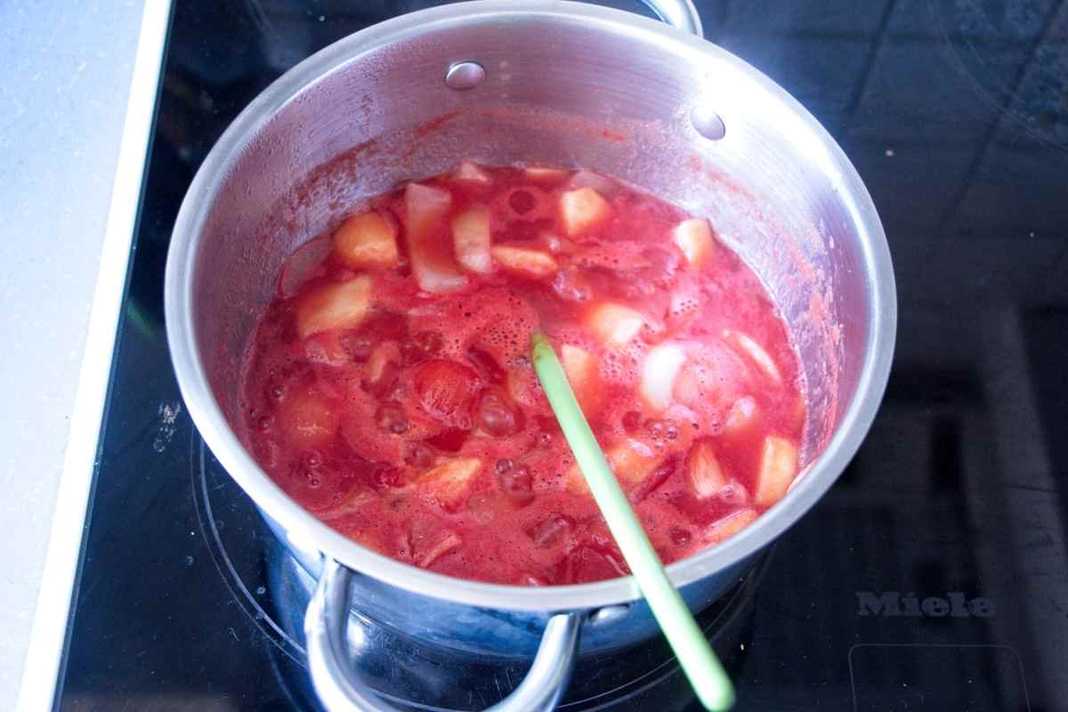 Tomatoes, apple and onion cooking in a saucepan to make brown sauce base