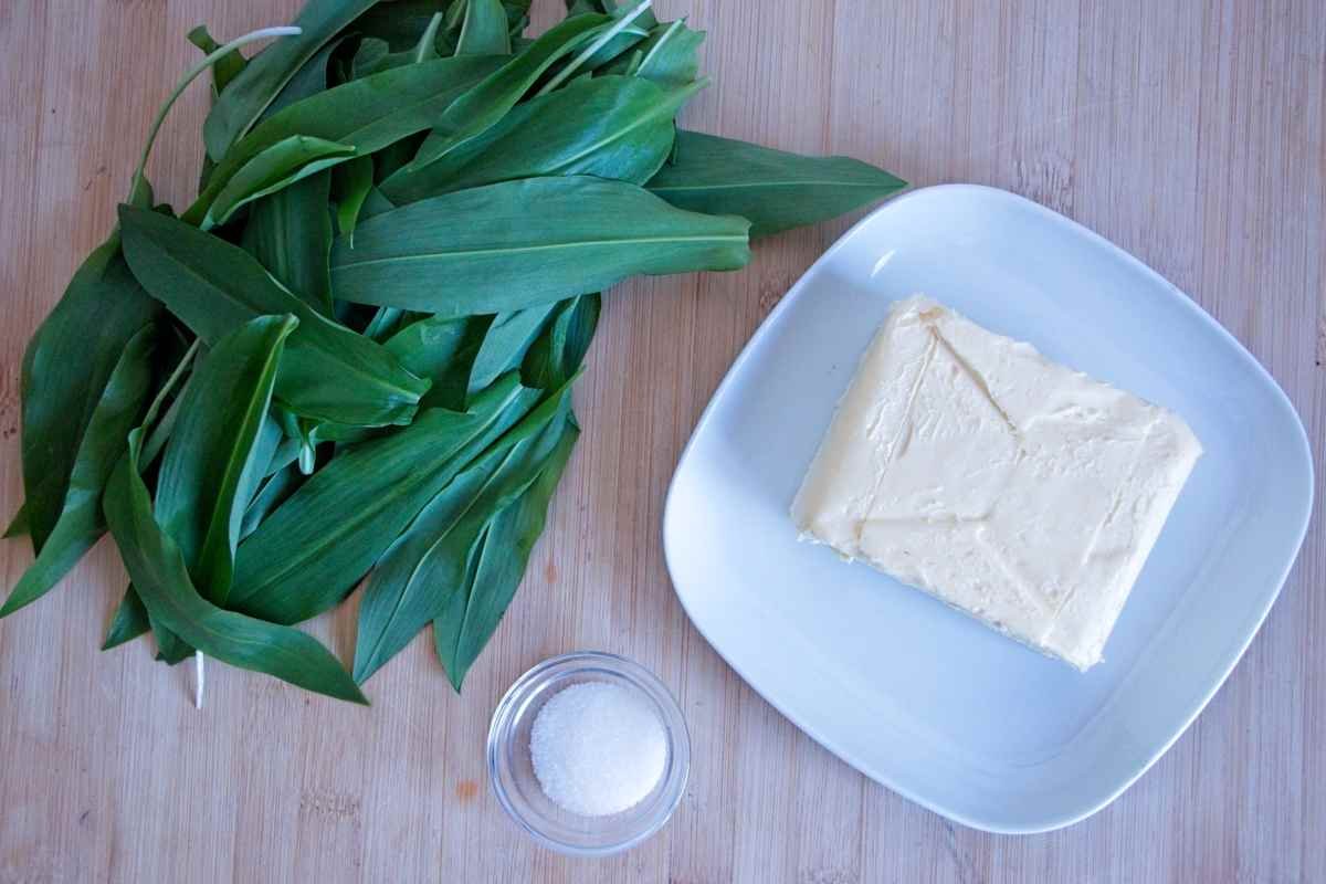 Wild garlic butter ingredients with fresh leaves, butter, and salt on a wooden board