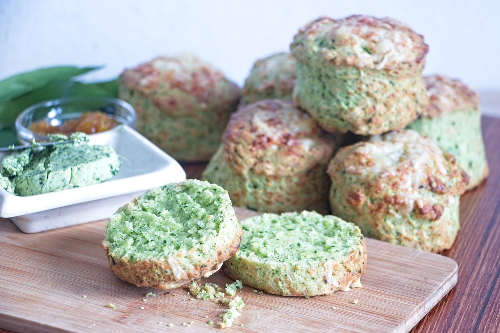 Wild garlic cheese scones stacked on a board with a cut scone showing the green interior