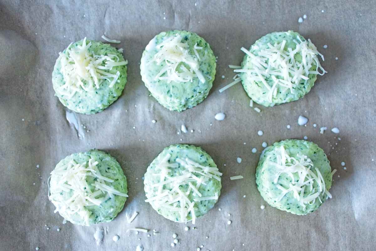 Wild garlic cheese scones unbaked on a tray, topped with grated cheddar before baking