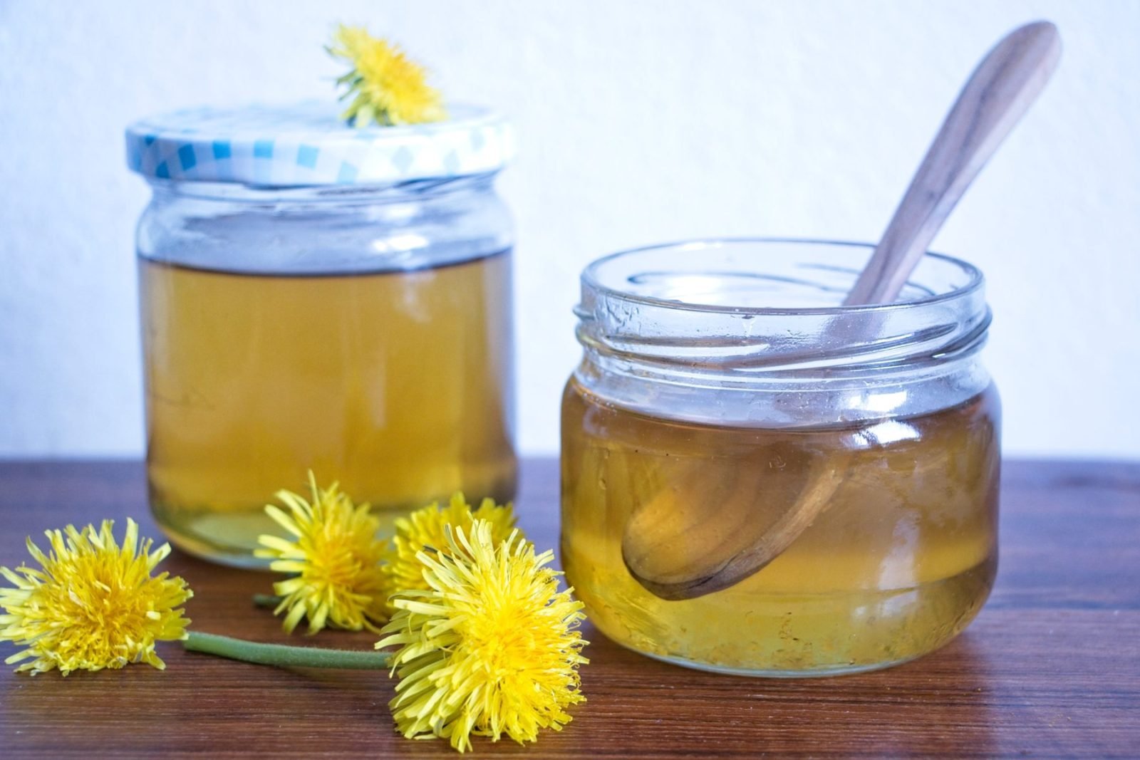 homemade dandelion honey with spoon and wild dandelions