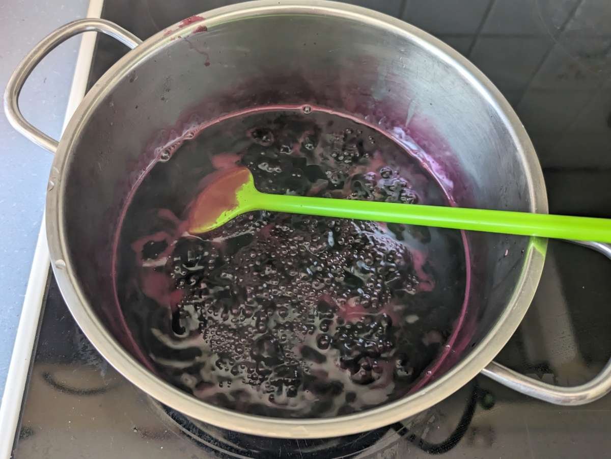 Elderberry jelly boiling in a saucepan until it reaches setting point