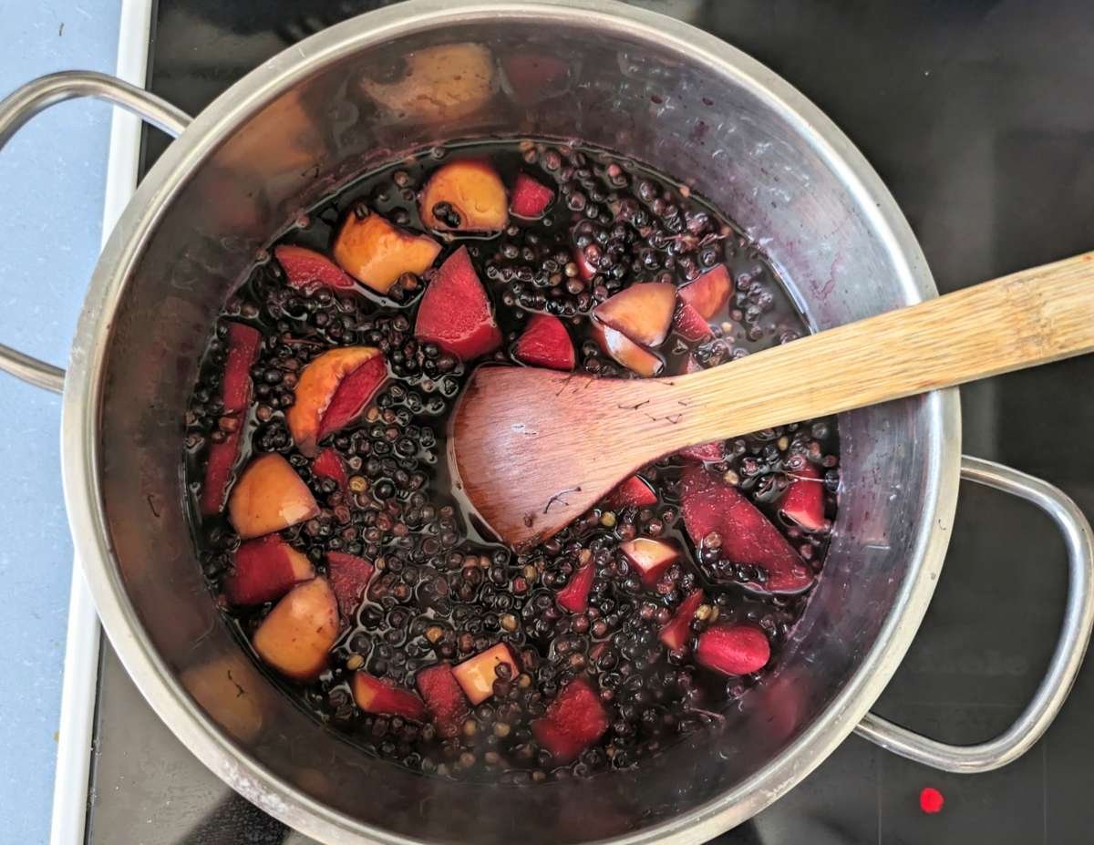 Elderberries and chopped apple simmering in a saucepan