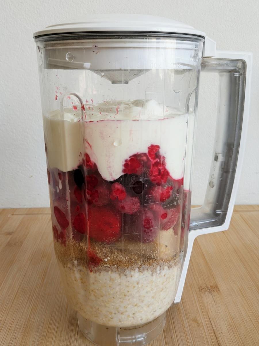 High fibre berry smoothie bowl ingredients layered in a blender before blending.