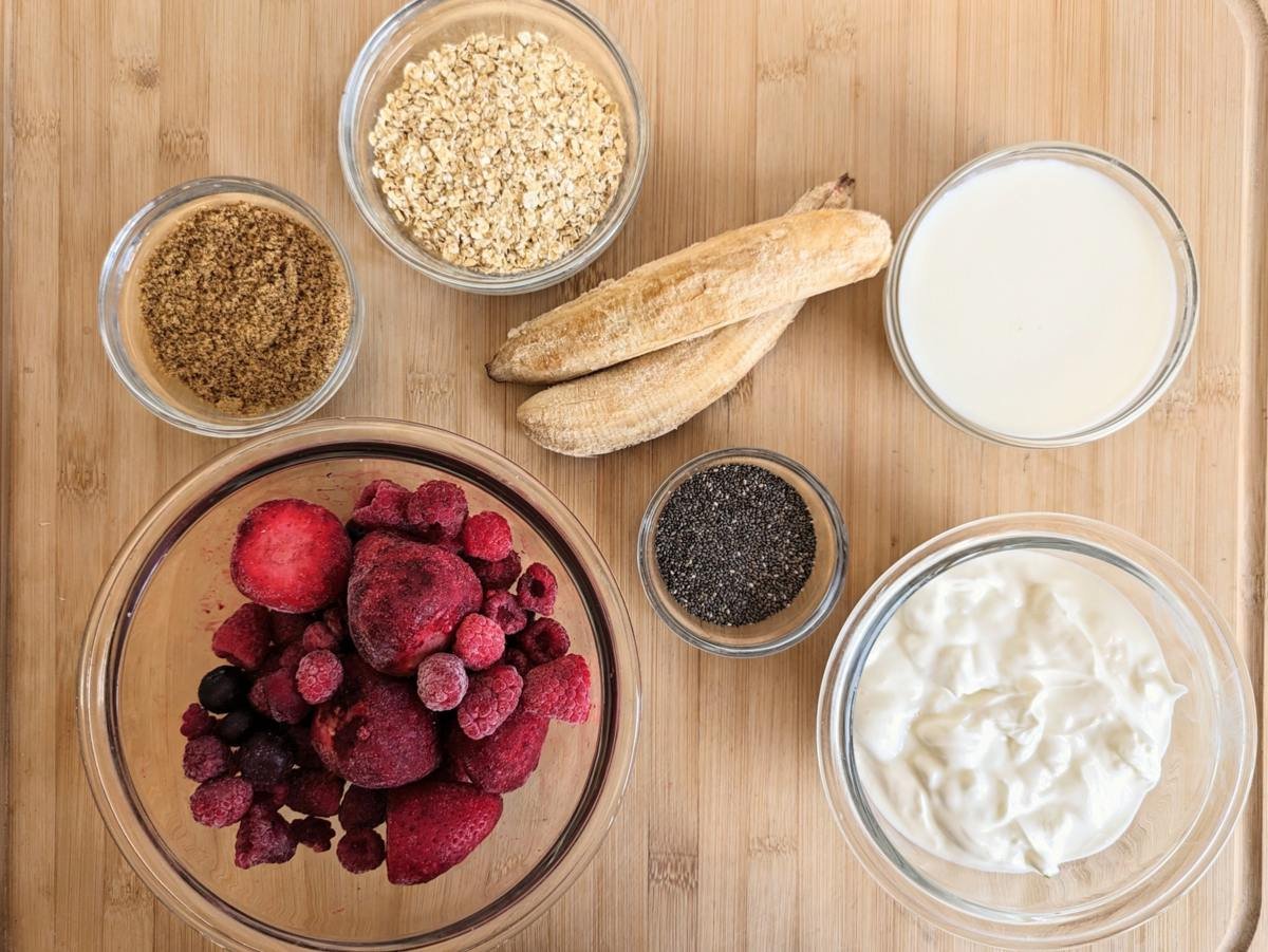 Ingredients for a high fibre berry smoothie bowl including frozen berries, banana, oats, chia seeds, flaxseed, Skyr and milk.