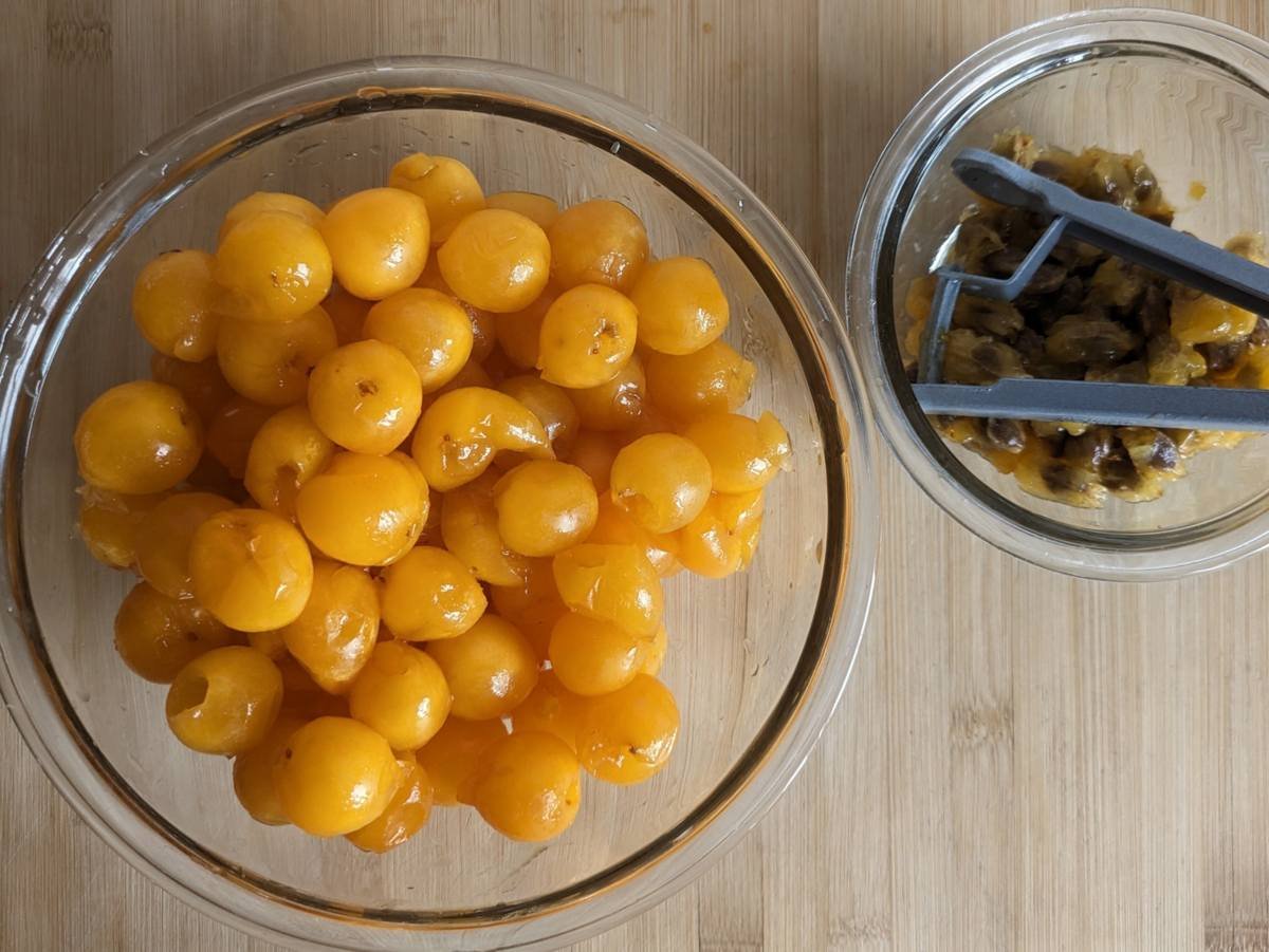 Mirabelle plums after pitting, with the stones collected in a separate bowl.