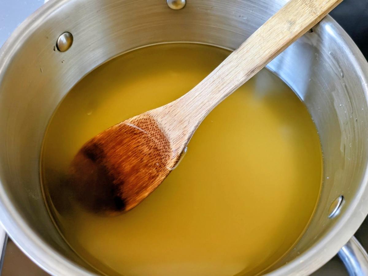 Strained plum juice with sugar being stirred to make homemade plum cordial.
