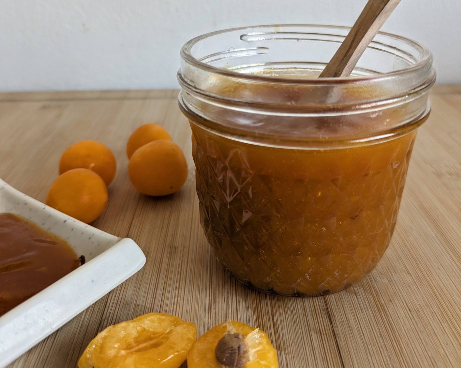 Jar of homemade slow cooker spiced plum butter with fresh Mirabelle plums.