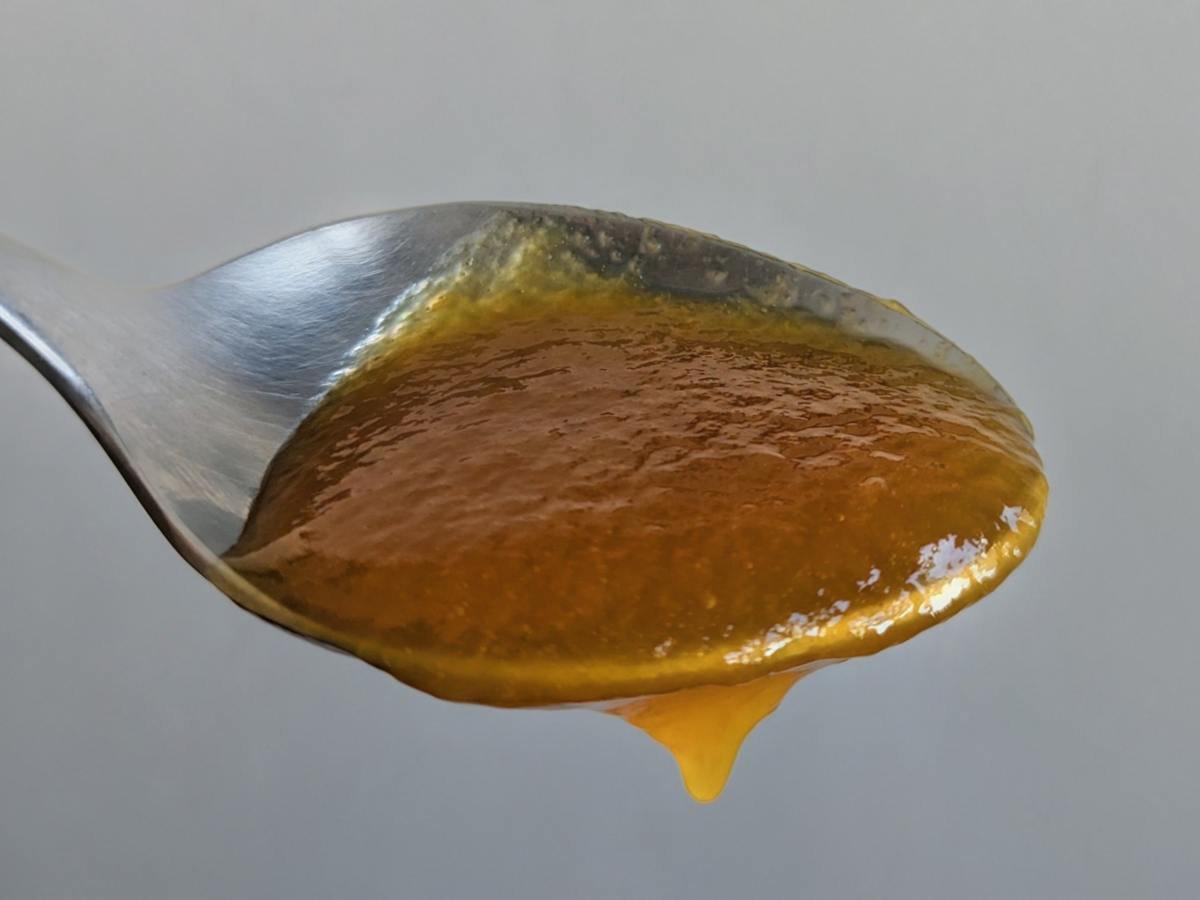 Close-up of the thick, spreadable texture of homemade slow cooker spiced plum butter on a spoon.