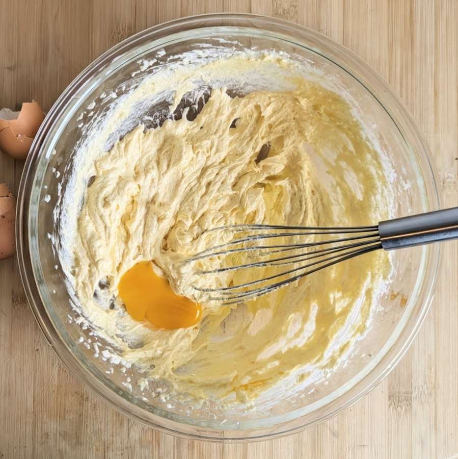 Adding an egg to the creamed butter and sugar mixture for the cake batter.
