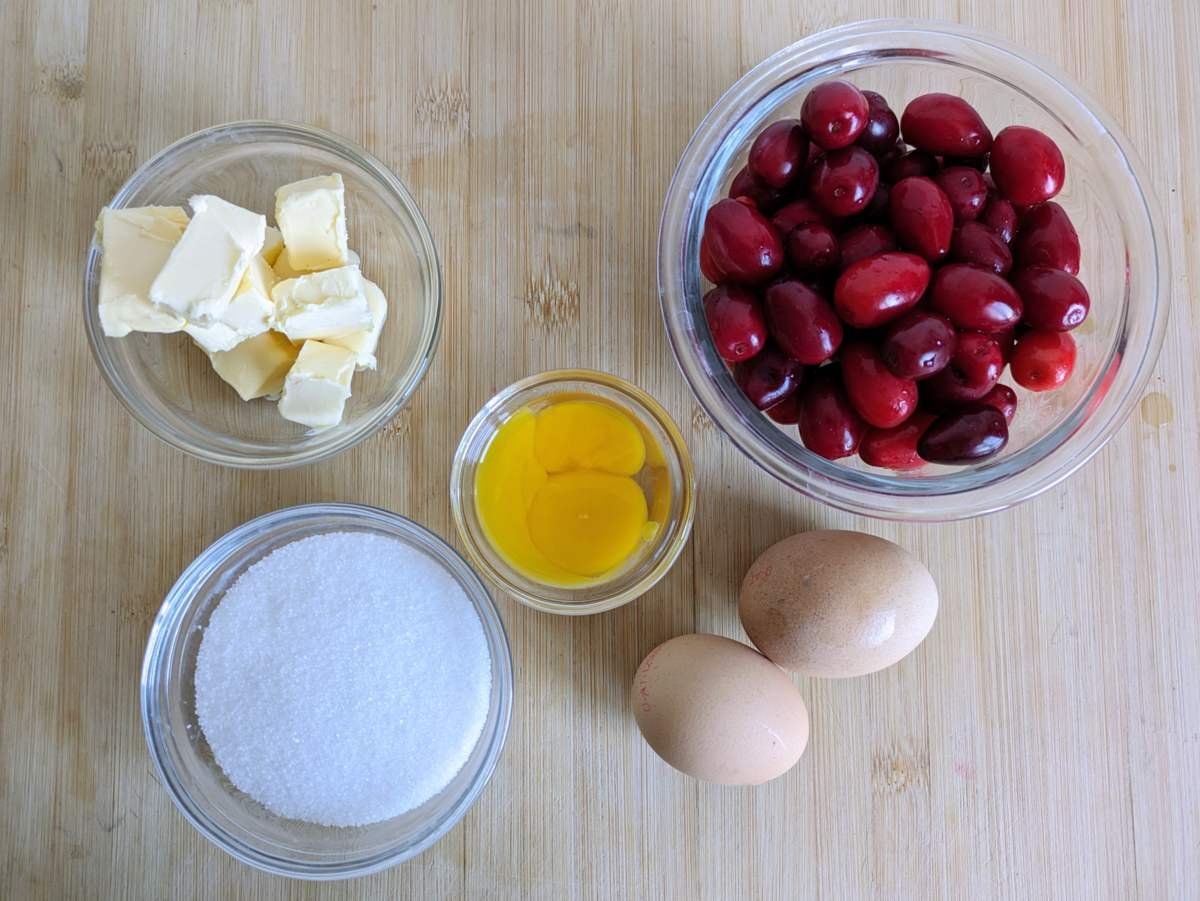Cornelian cherries, eggs, sugar and butter for making fruit curd.